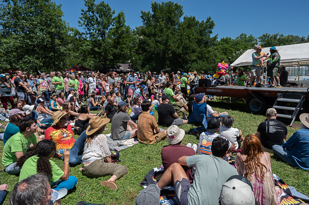 A bunch of people sitting and standing around a stage waiting for the entertainment to begin. 